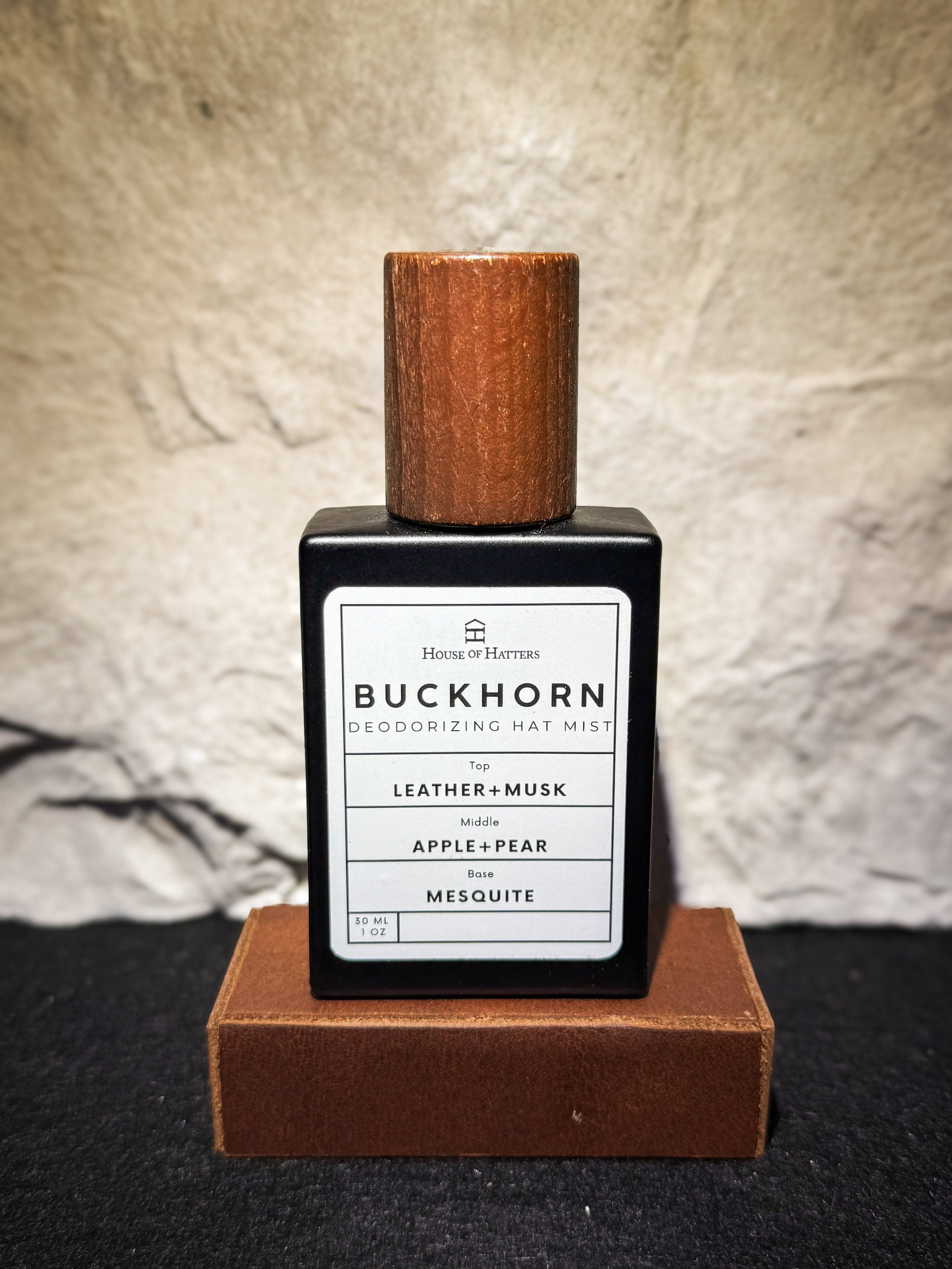 Buckhorn deodorizing hat mist bottle with wooden cap on a textured surface