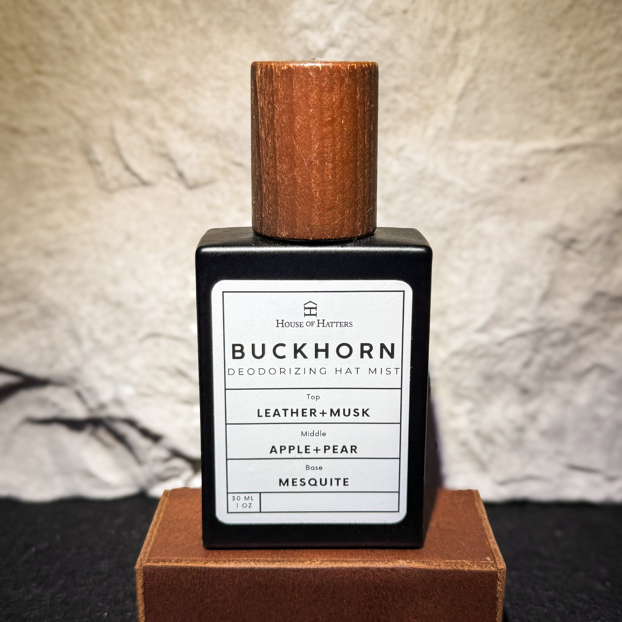 Buckhorn deodorizing hat mist bottle with wooden cap on a textured surface