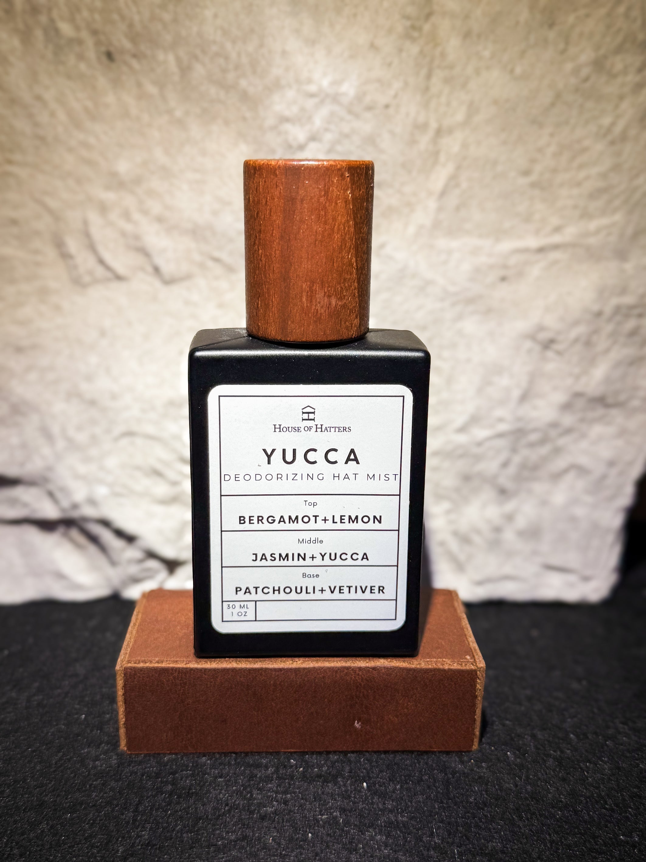 Yucca deodorizing mat mist bottle with wooden cap on a textured surface