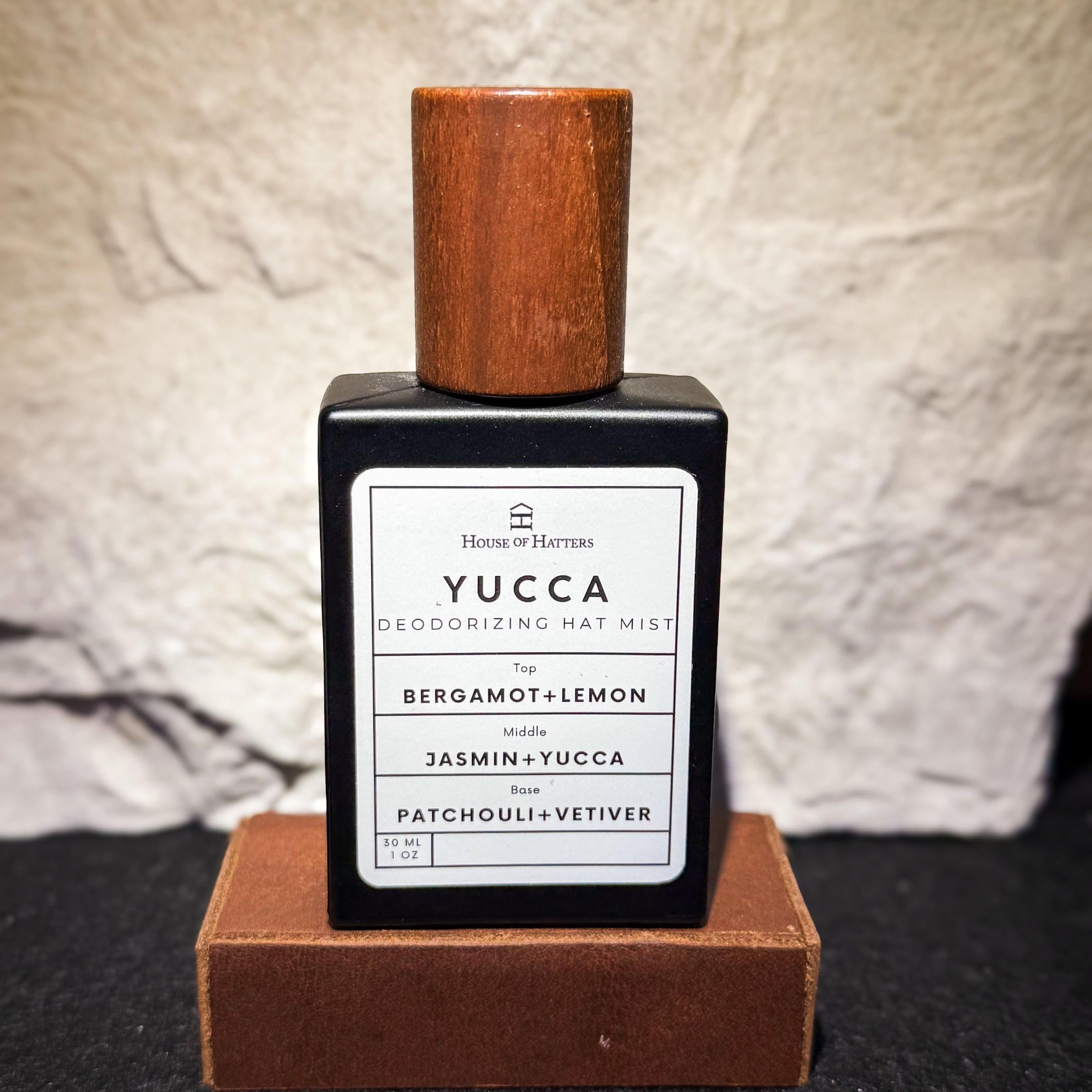 Yucca deodorizing mat mist bottle with wooden cap on a textured surface