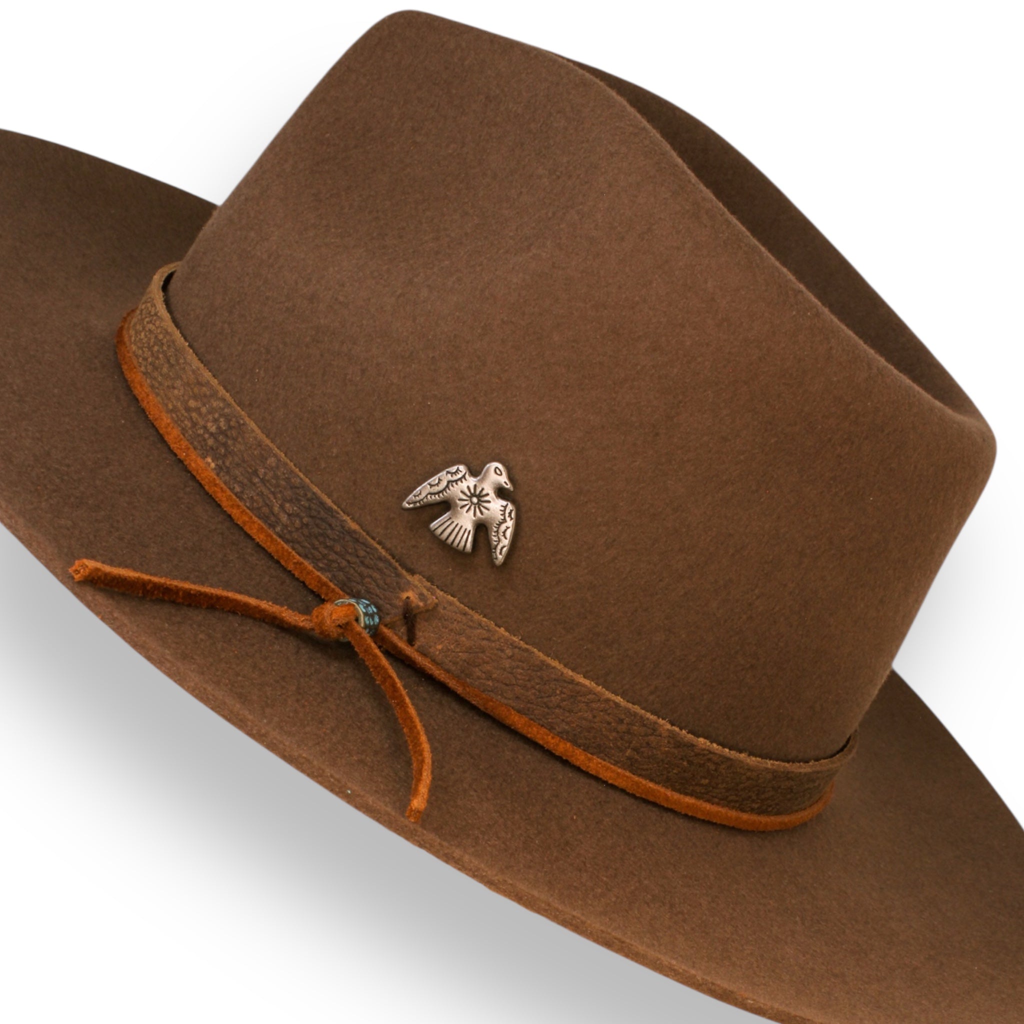 A closeup view of the accessories on the felt fedora hat. The accessories are a silver bird, a brown leather band, and a rust orange hat tie.