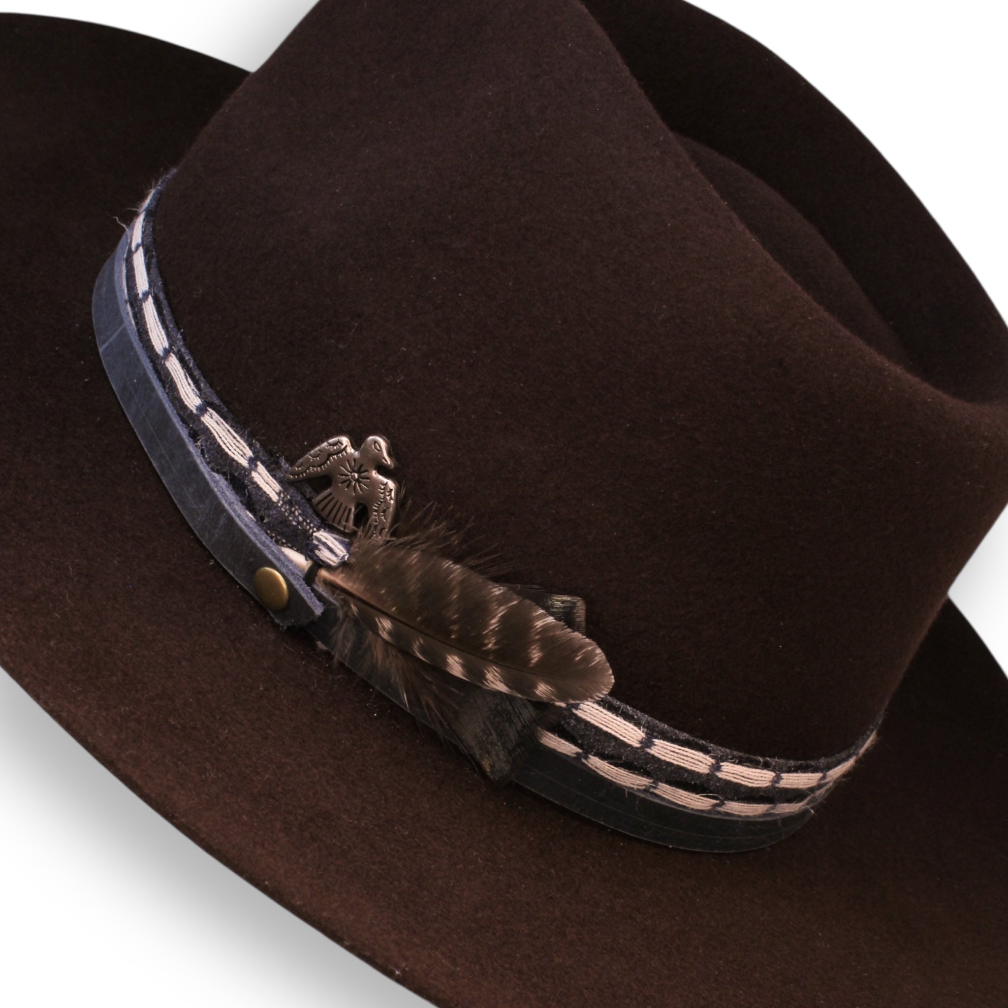 A closeup of the chocolate hat with a small striped feather and a silver thunderbird concho.