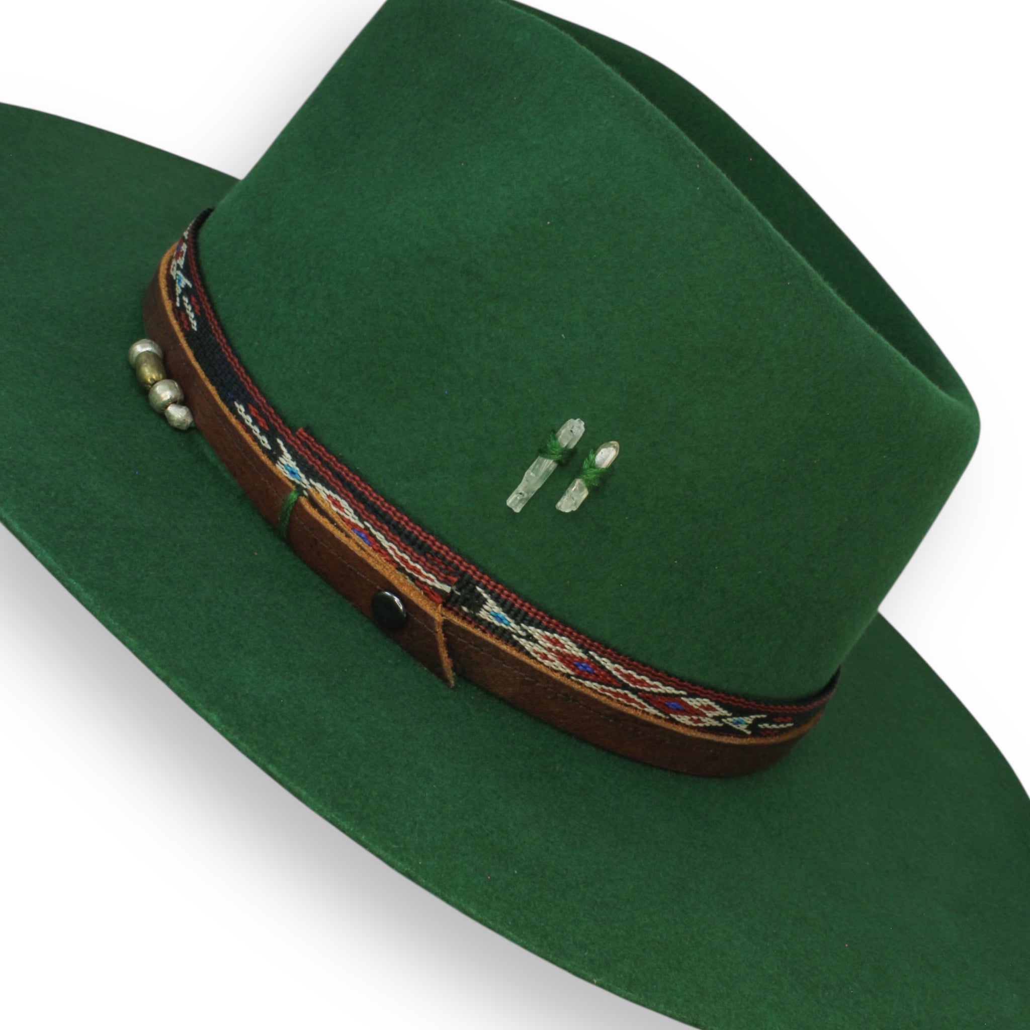 Detailed shot of an emerald green felt fedora with two small quartz crystals and silver and brass beads.
