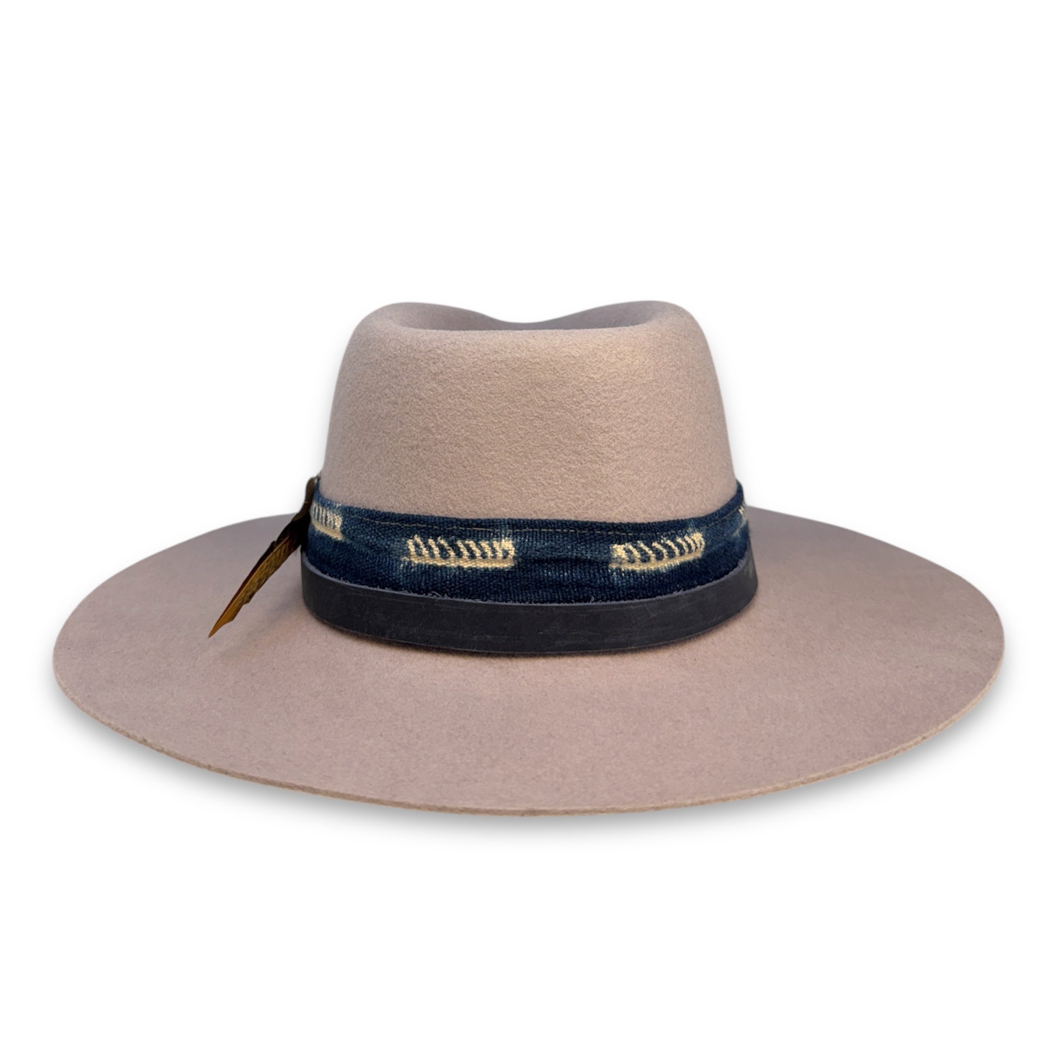 The back view of a light off-white colored hat with a handmade textile band and a leather hat band.