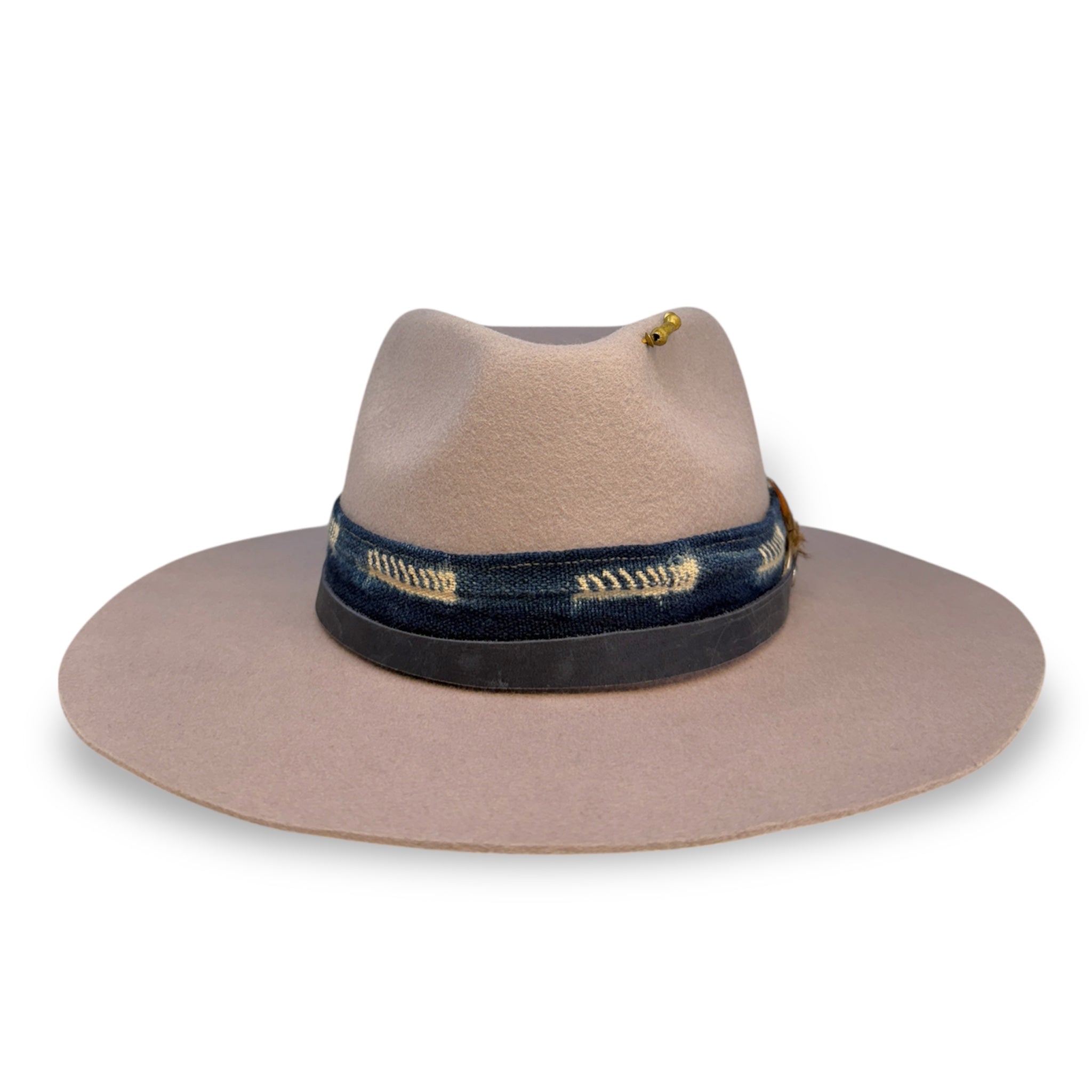 The front view of a lavender wide brim fedora with a wide front pinch, brass beads, and blue hat and textile bands.