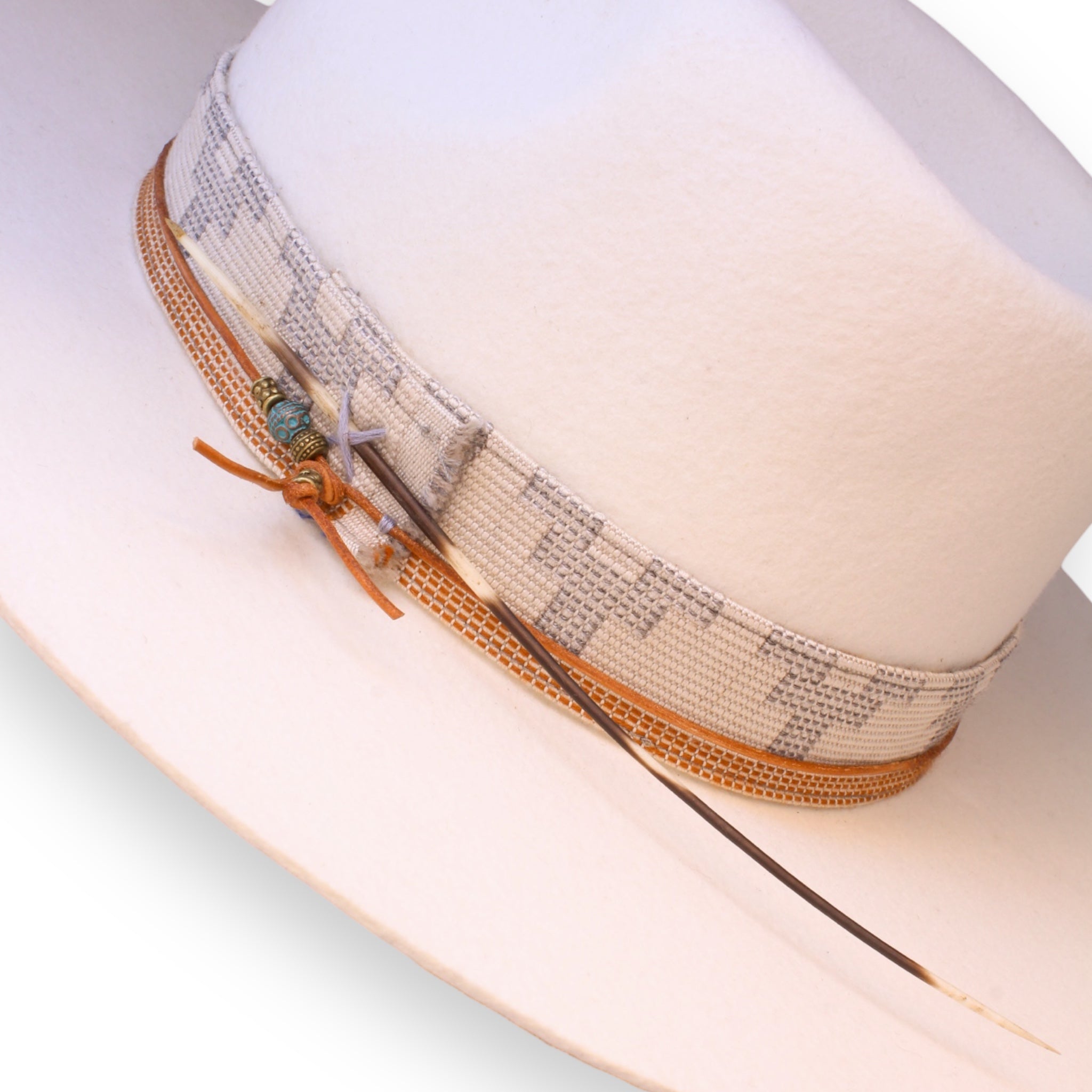 Detailed shot of a white fedora. This photo shows off the beautiful white and orange textile band, the orange hat tie with brass and blue beads, and a large porcupine quill.